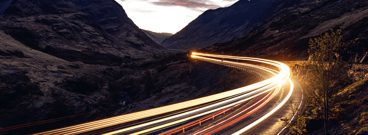 Image of motion blur car lights on a road in the mountains during late evening
